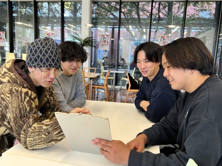 初等教育コースの仲間と一緒に空きコマの時間を楽しむKさん（写真右奥）。